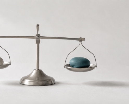 A balance scale holding a small white stone and a larger teal stone, representing the decision between a filling and a crown.