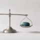 A balance scale holding a small white stone and a larger teal stone, representing the decision between a filling and a crown.