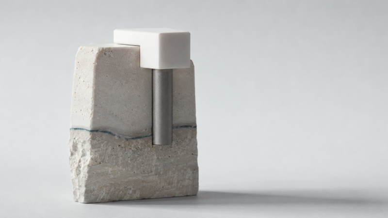 A titanium post anchored into layered stone with a white cap seated on top, representing the surgical and restorative stages of implant treatment.