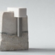 A titanium post anchored into layered stone with a white cap seated on top, representing the surgical and restorative stages of implant treatment.