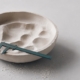 A plaster casting mould with a teal calliper resting in it, representing the denture fitting and adjustment process.