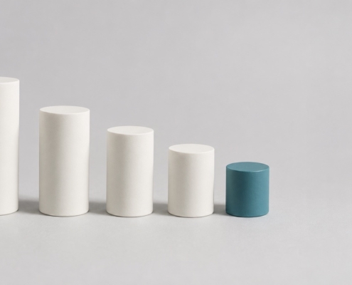 Five ceramic cylinders in a descending row, the smallest in teal, representing the sequential stages of root canal treatment.