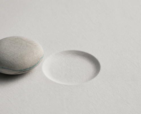 A single stone beside an empty indentation of the same size, representing the choice between saving and removing a tooth.
